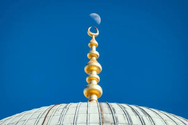 Top of old and beautiful Sultan Ahmed Mosque (Blue Mosque) Ottoman imperial mosque located in Istanbul, Turkey. Moon and sky in background.