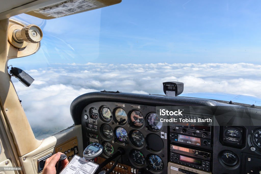 View from a cockpit of an aircraft View from a cockpit of a small engine vehicle over an almost closed cloud cover Cockpit Stock Photo