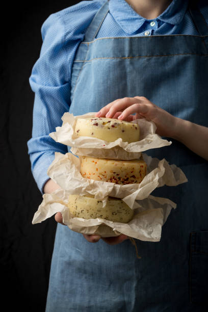 istock Woman holding assorted cheese head in blue apron on dark background 1058505816