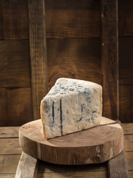 Slice of blue cheese on wooden board on dark background stock photo