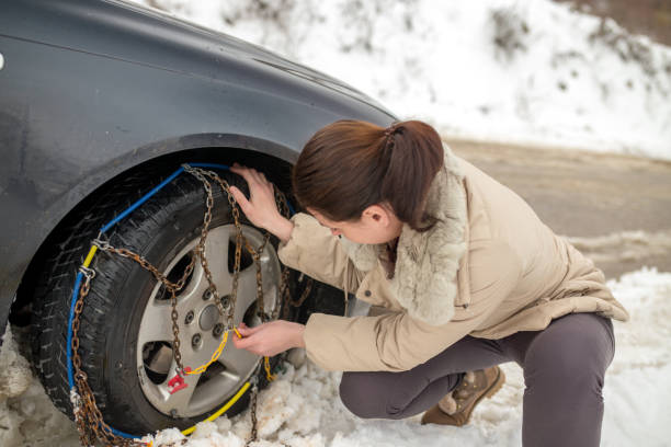 istock Beautiful woman installing snow chain on her car 1058510504