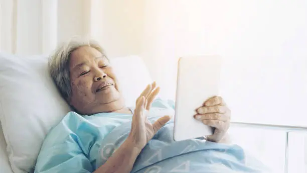 Elderly patients in hospital bed patients using smart phone call to descendant relatives feel happy ness - medical and healthcare concept