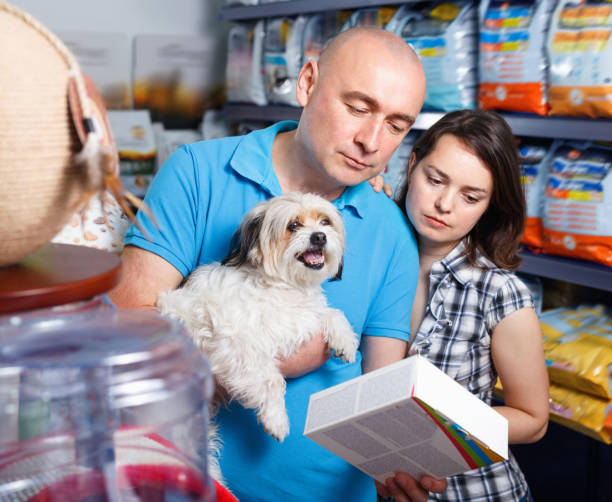 Portrait of  family couple with dog  choosing dry food in pet store Portrait of glad  cheerful family couple with dog  choosing dry food in pet store pet shop photos stock pictures, royalty-free photos & images