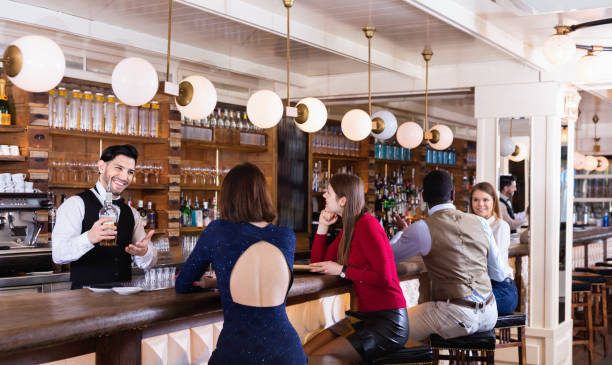 istock Barman is servicing young people who are relaxing in bar indoor. 1058529612