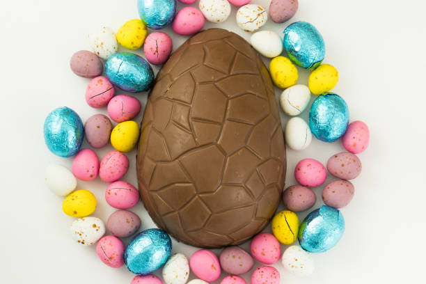 istock Colorful circle of Easter eggs blue pink yellow purple and white on a white studio background with large chocolate egg in the center 1058536406
