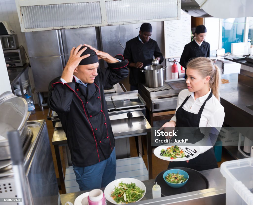 Desnorteado chef falando com garçonete - Foto de stock de Cozinha comercial royalty-free