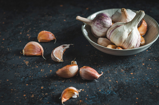 Garlic cloves on rustic table. Garlic in bowl. Fresh peeled garlic and bulbs.