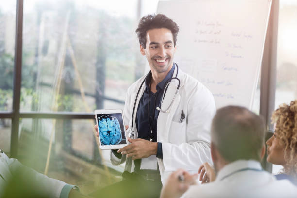 médecin de sexe masculin actions cerveau aux rayons x avec vos collègues - doctor digital display digital tablet healthcare and medicine photos et images de collection