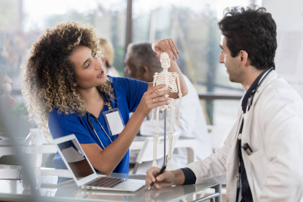 istock Female doctor uses human skeletal model as visual aid 1058542220