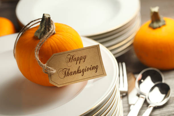istock Happy Thanksgiving Tag Hangs From A Pumpkin And Rests On Stack Of Plates 1058543282