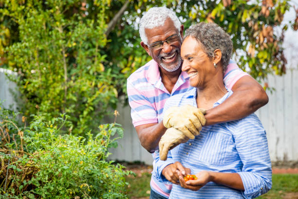 adorabile coppia nera che lavora insieme in giardino - gardening couple senior adult ethnic foto e immagini stock