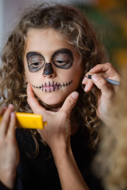 istock Little goth girl putting make-up on face, looking in small yellow mirror 1058566010