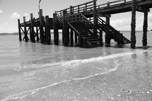Long concrete steps forming a sea defence along the coast with waves and sand at the shoreline in monotone