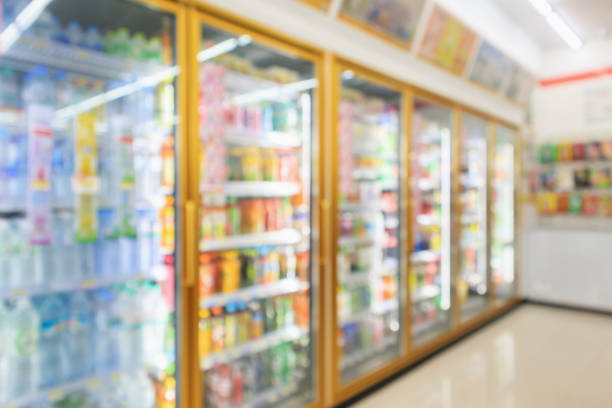 супермаркет магазин холодильники с бутылками безалкогольных напитков на полках абстрактного фона размытия - convenience стоковые фото и изображения