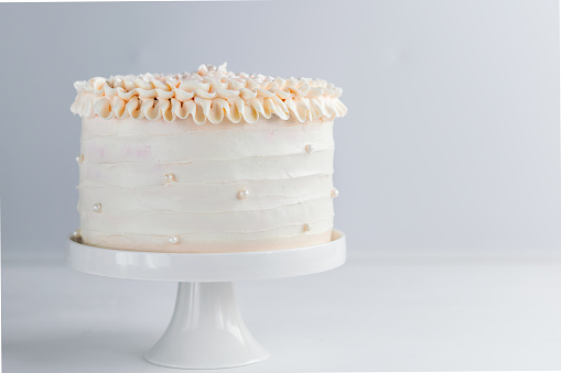 Beautiful Birthday Cake decorate with edible pearls on white neutral background. Copy space. Celebration concept. Trendy Layer Cake. Horizontal.