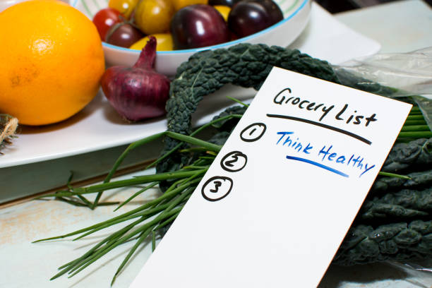 Grocery list on rustic wood counter with fresh fruits and vegetables conceptual healthy organic food and lifestyle concept Healthy lifestyle and healthy diet conceptual photography grocery list on kitchen counter with fresh market fruits and vegetables including citrus fruit and superfood kale with chives and tomatoes handwritten words Grocery List with motivation message for New Years résolution to Think healthy 2019 new year resolution stock pictures, royalty-free photos & images