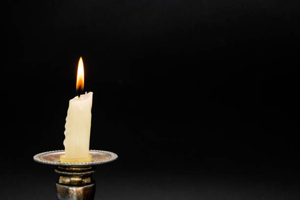 lighted candle in an old candlestick on a black background - fire heat ornate dirty imagens e fotografias de stock