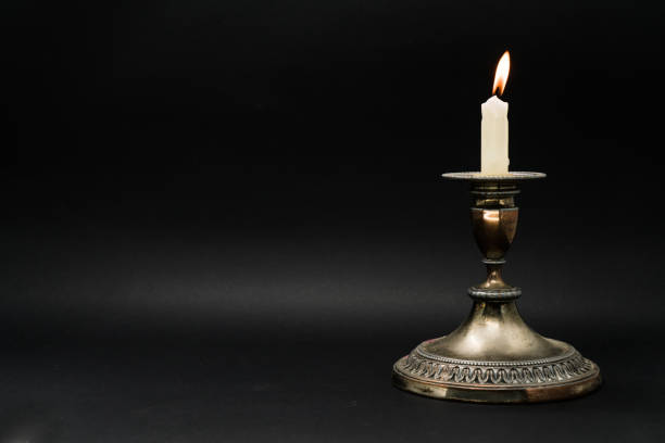 istock Lighted candle in an old candle holder isolated in black background with copy space 1058593444