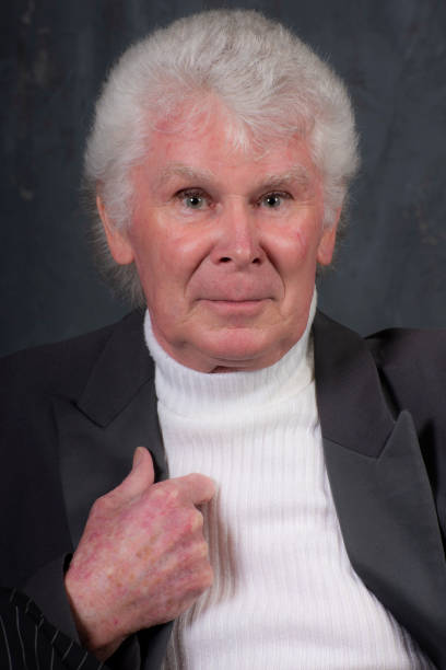 70 year old man smiles at camera.