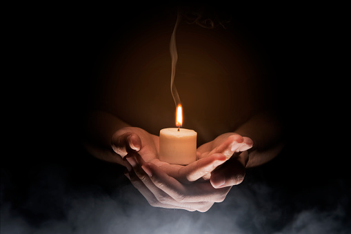 Hands holding candle over dark background. Christian Pray