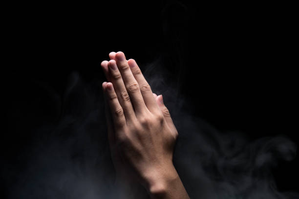 istock Hands with praying gesture over dark background 1058628560