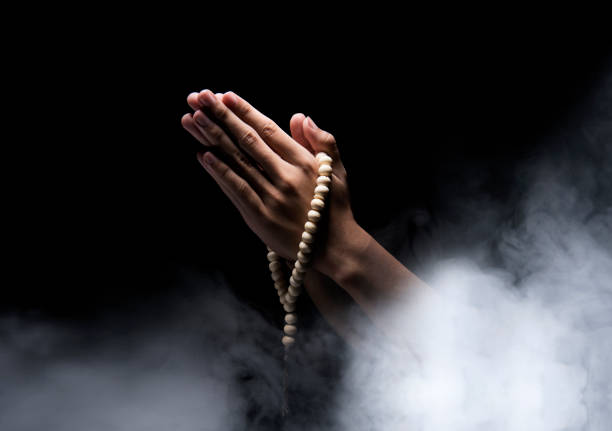 Man hands praying with prayer beads over dark background. Muslim Pray