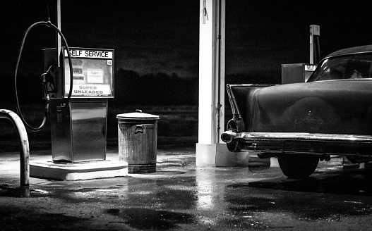A classic American car refuels at an old-fashioned gas station.