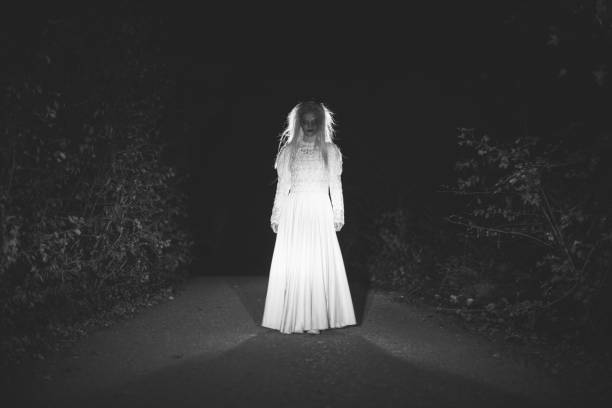 Witch in white One woman, she masked herself in a scary witch for halloween, standing on the street, black and white. ghost photos stock pictures, royalty-free photos & images