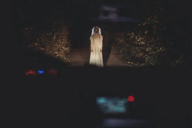 One woman, she masked herself in a scary witch for halloween, standing in front of a car.