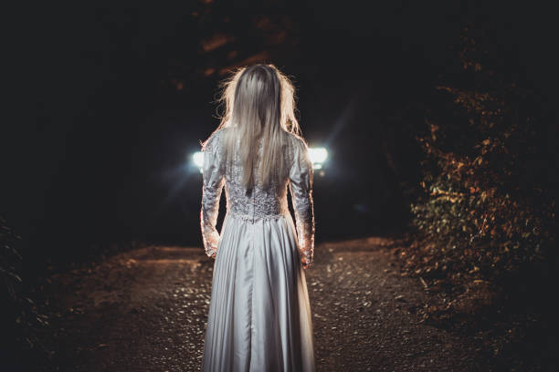 istock Witch in white in front of a car 1058640846