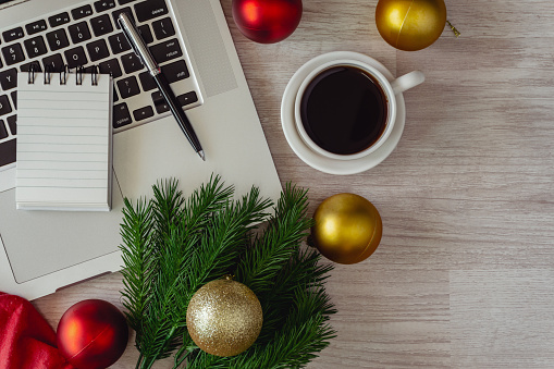 Laptop and notepad with ornaments balls on wood table. Office table on Christmas.