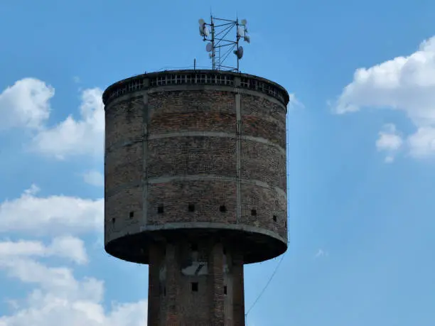 old brick water tower converted to radio or cell transmitter tower under blue sky