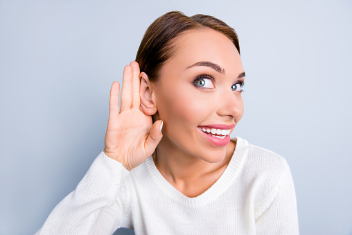 Close up portrait of funny curious woman holding palm near ear listening gossips eavesdropping talk isolated on grey background