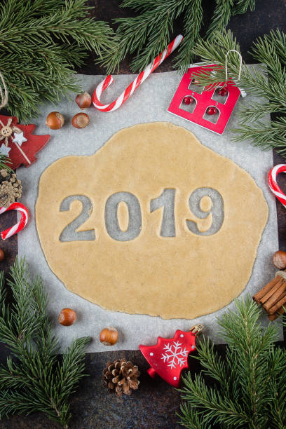 urlaub cookies, bäckerei zum neujahr zu feiern. rohen teig fertig zum backen von lebkuchen in form 2019. weihnachten dekoration und tanne zweig auf tisch - candy cane christmas cookie raw food stock-fotos und bilder