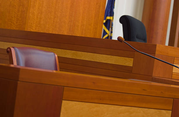 Silent Witness An empty witness box (foreground) and judge's bench (background) in a modern courtroom. witness stock pictures, royalty-free photos & images