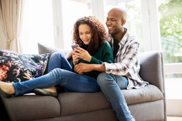 istock Man sitting with woman using smart phone on sofa 1058656882