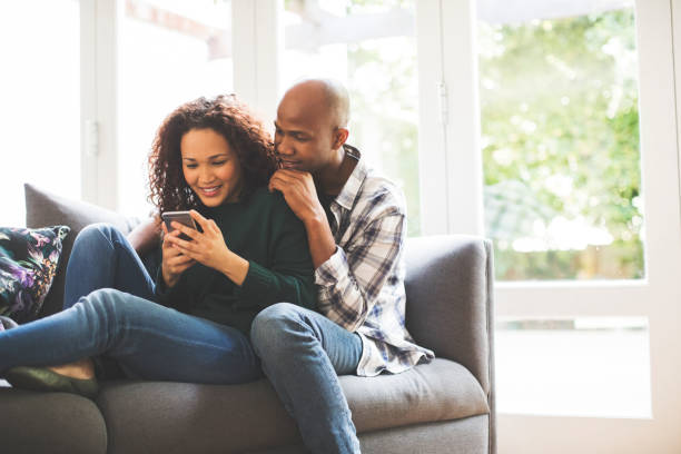 istock Smiling man sitting with woman using smart phone 1058656896