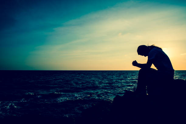 silhouette women sitting alone on the rock. mental health, ptsd and suicide prevention. - solicitous imagens e fotografias de stock