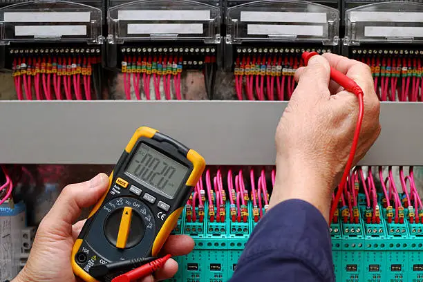 Technician testing a control panel wiht measurement instrument, close-up