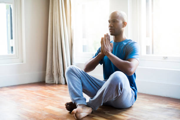istock Man practicing yoga against window in apartment 1058663518