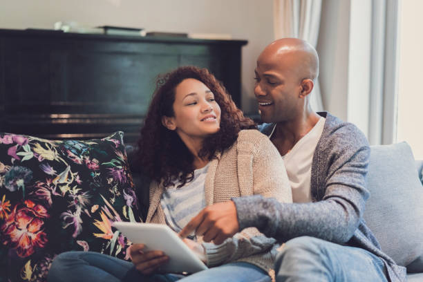 istock Smiling couple sitting with digital tablet on sofa 1058666628
