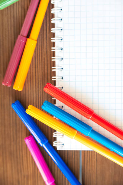istock Multicolored felt pens with notebook on wooden background. Recreation concept drawing 1058666998
