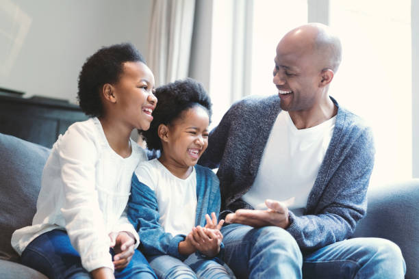istock Cheerful father enjoying with daughters on sofa 1058668726