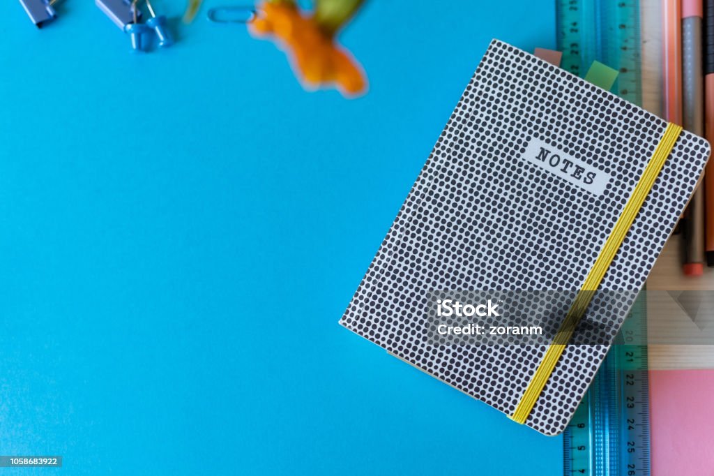 Black and white notepad with rubber band Black and white notepad with rubber band on desk with ruler, pens and pins Note Pad Stock Photo