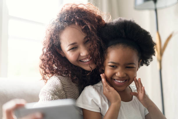 istock Smiling mother taking selfie with daughter at home 1058684032