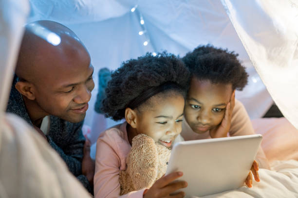 istock Father looking at girls using digital tablet 1058690532