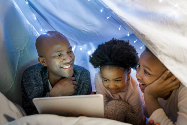 istock Girls using digital tablet by father in tent 1058690534