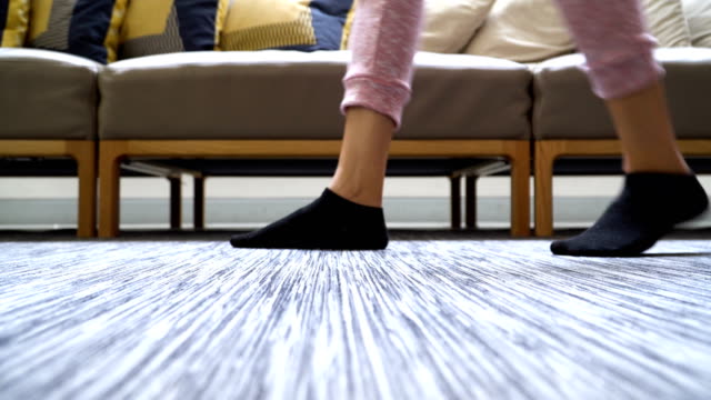 low angle view on the floor: woman's feet with sock walking in domestic room