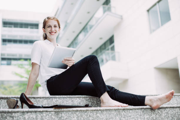 istock Happy barefoot student with digital tablet outdoor 1058702138