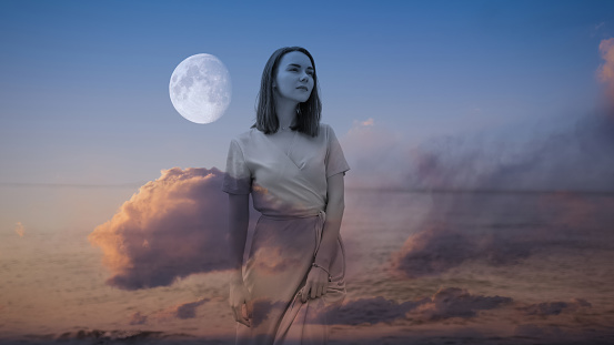 Double exposure of young woman and sunset sky.